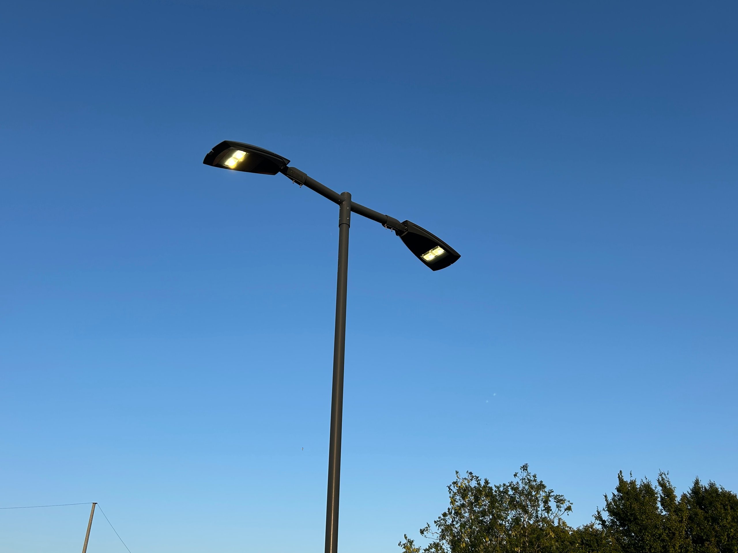 Modern streetlight illuminated against evening sky